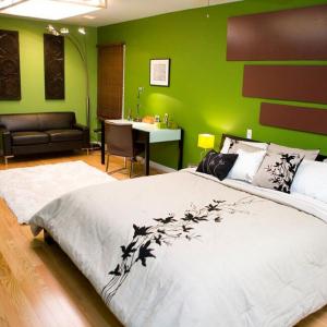 Модерната спалня притежава обзавеждане от дърво и зелени стени