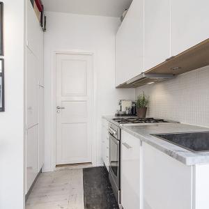 Кухнята впечатлява с изчистен дизайн, като оползотворява тесния коридор